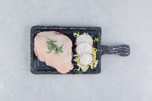 Foto gratuita pechugas de pollo crudas y especias en el tablero, sobre la superficie blanca