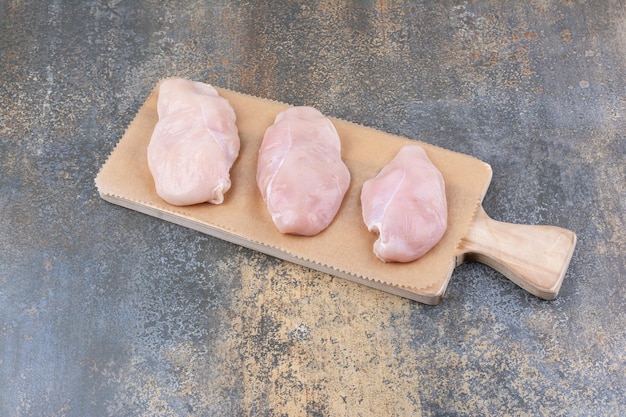 Pechugas de pollo crudas sobre tabla de madera. Foto de alta calidad