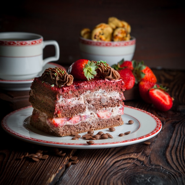 pedazo de pastel con fresas y migas y una taza de té en un plato