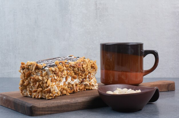 Un pedazo de pastel con una taza de café aromático en la mesa gris.