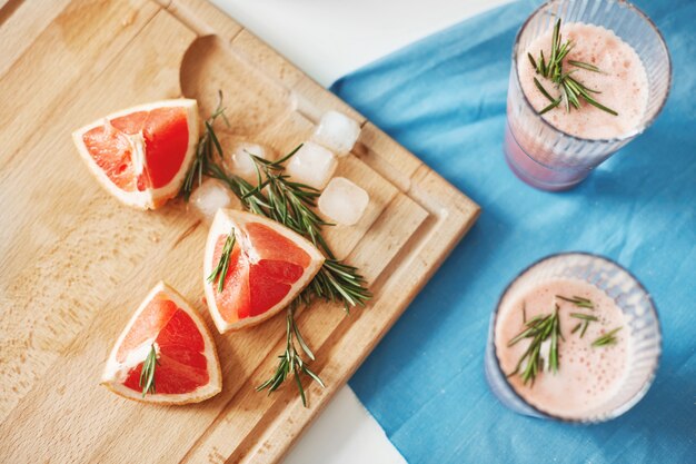 Pedazos de pomelo y romero en el escritorio de madera. Batido de dieta de desintoxicación saludable. Concepto de pérdida de peso de fitness. Desde arriba.