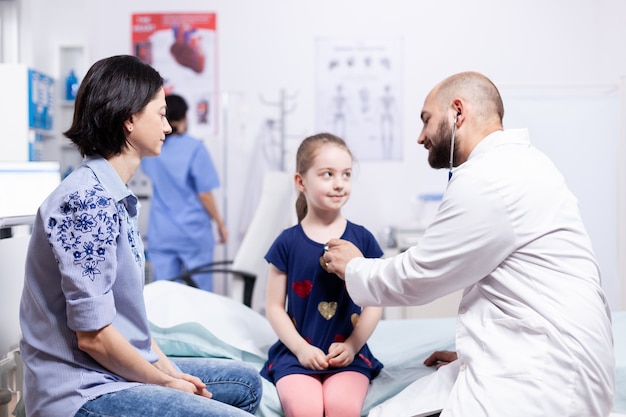 Pediatra que controla la salud del niño con estetoscopio en la oficina del hospital durante la consulta. Médico especialista en medicina que brinda servicios de atención médica. Examen de tratamiento.