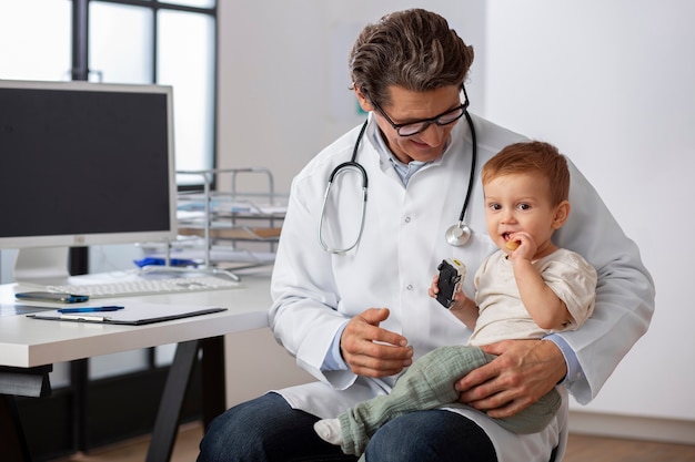 Pediatra sosteniendo a un niño pequeño para una consulta