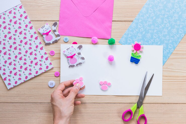 Foto gratuito pegatina de decoración de mano de una persona en papel blanco sobre la mesa de madera