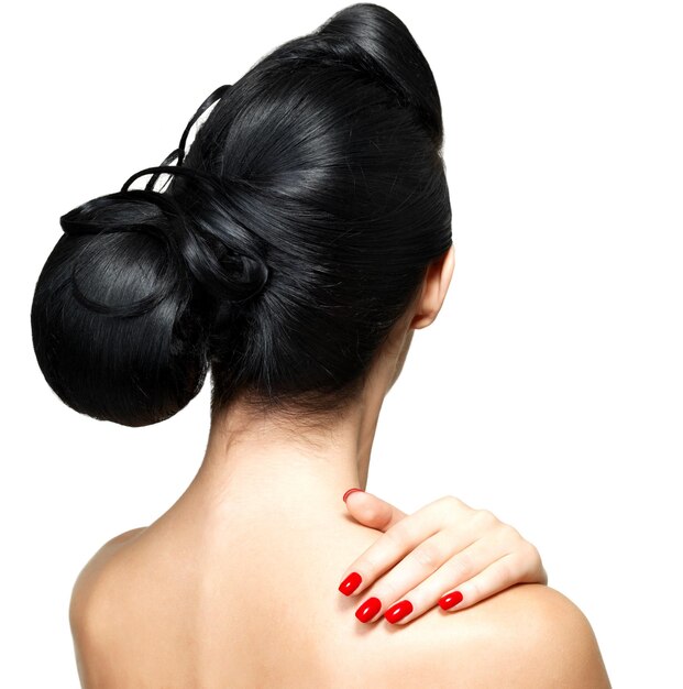 Peinado de moda de mujer con uñas rojas aislado en pared blanca