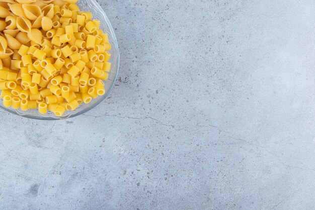 Pele la pasta cruda con Ditali Rigati seco y crudo en un recipiente de vidrio.