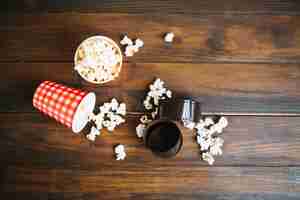 Foto gratuita película enrollada y tazas con palomitas de maíz