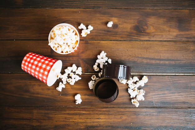 Película enrollada y tazas con palomitas de maíz