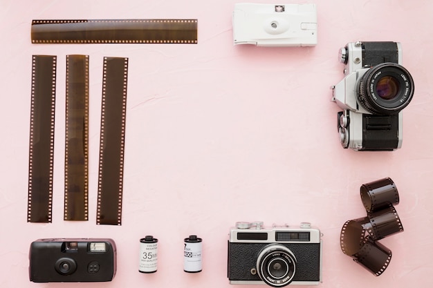 Película fotográfica y cámaras sobre fondo rosa