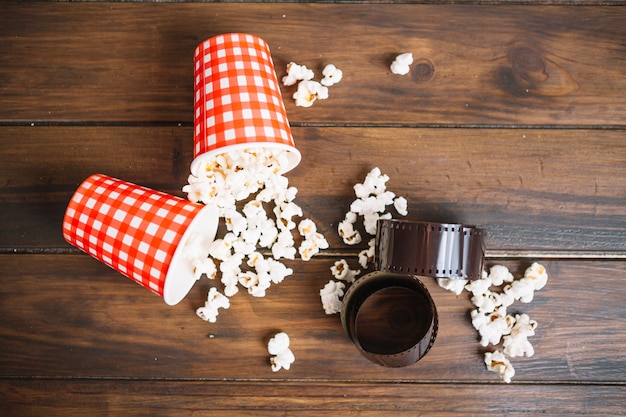 Película y tazas con palomitas de maíz derramadas