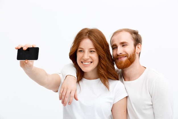 Pelirroja feliz hombre y mujer toman selfie