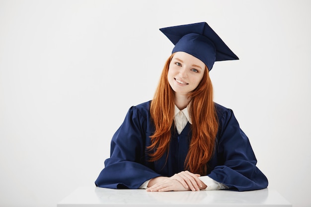 Pelirroja mujer graduada sonriendo.