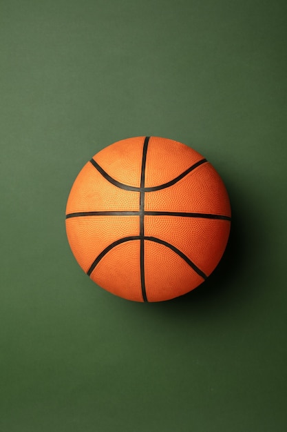 Pelota de baloncesto naranja-braun brillante. Equipo de deporte profesional aislado sobre fondo verde de estudio. Concepto de deporte, actividad, movimiento, estilo de vida saludable, bienestar. Colores modernos.