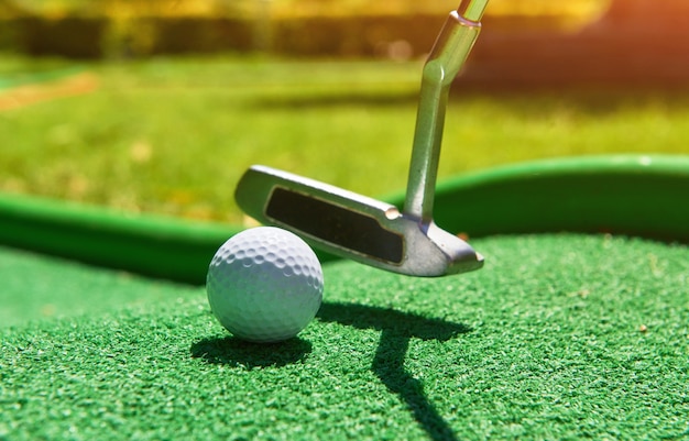Pelota de golf y club de golf sobre césped artificial.