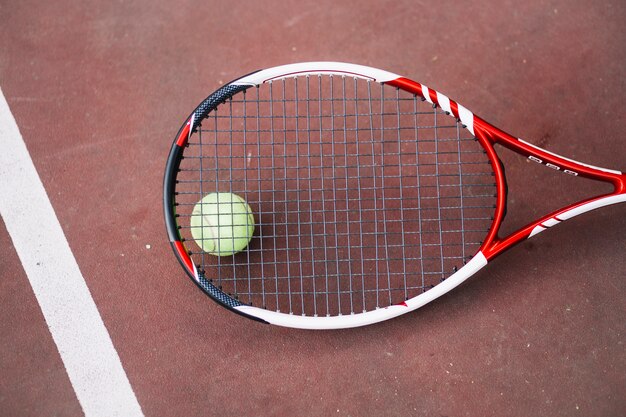 Pelota de tenis de alto ángulo con raqueta al lado