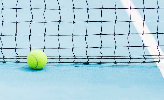 Foto gratuita pelota de tenis con fondo de pantalla en negro sobre una dura cancha de tenis azul