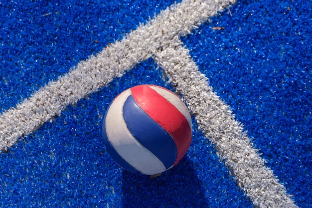 Foto gratuita una pelota de voley tirada en el campo deportivo azul lista para ser recogida