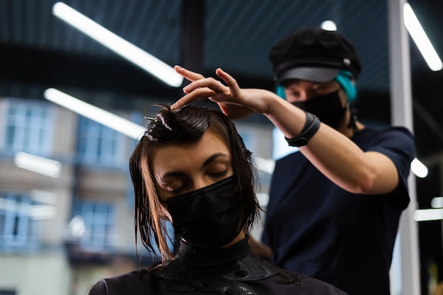 Una peluquera profesional hace el corte de pelo de un cliente. La niña está sentada en una máscara en el salón de belleza.