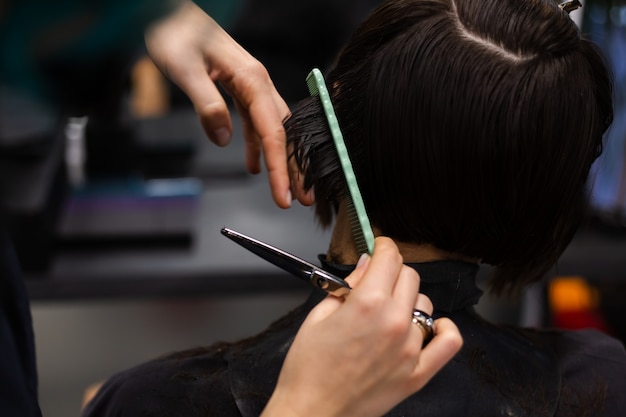 Una peluquera profesional hace el corte de pelo de un cliente. La niña está sentada en una máscara en el salón de belleza.