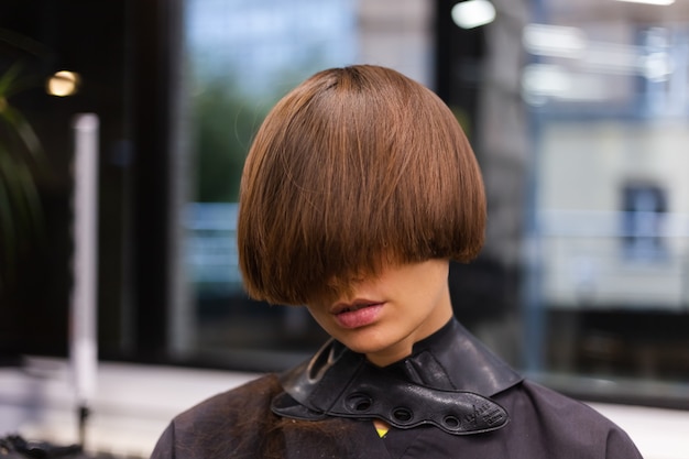 Una peluquera profesional hace el corte de pelo de un cliente. La niña está sentada en una máscara en el salón de belleza.