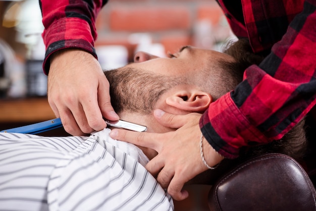 Peluquería afeitando a un hombre de barbas en peluquería