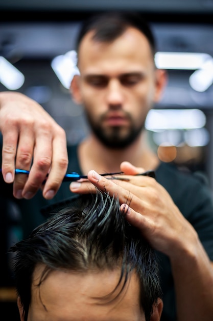 Peluquería borrosa cortando el cabello del cliente