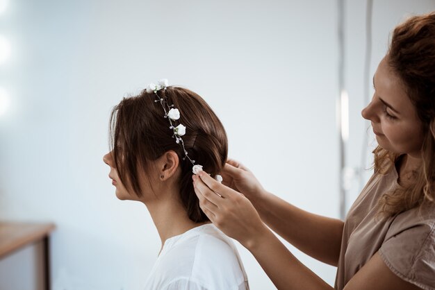 Peluquería femenina haciendo peinado a mujer morena en salón de belleza