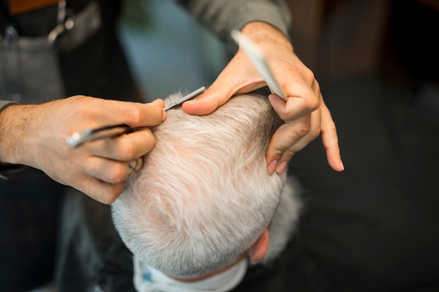 Foto gratuita peluquería haciendo corte de pelo al cliente en estudio