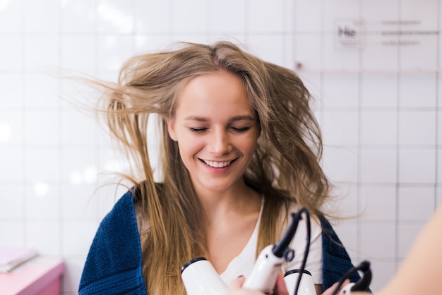 Foto gratuita peluquería de mujer joven con un secador de pelo en sus manos peinado mujer belleza cabello salón de belleza profesional