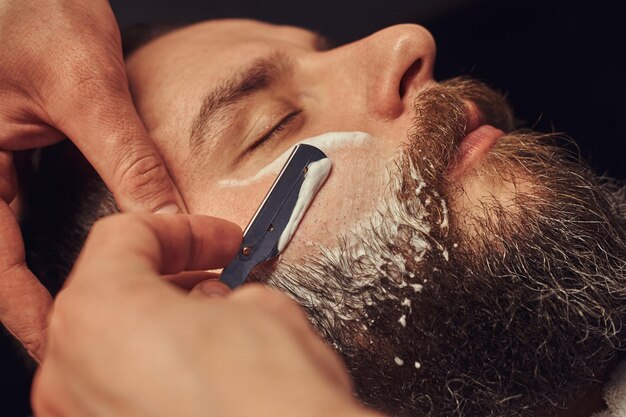 Peluquería profesional modelando barba en la barbería. Cerca de la foto.