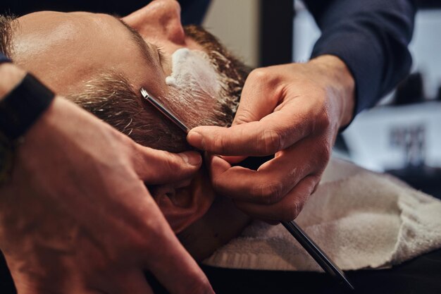 Peluquería profesional modelando barba en la barbería. Cerca de la foto.