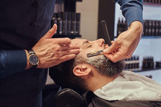 Peluquería profesional modelando barba en la barbería. Cerca de la foto.