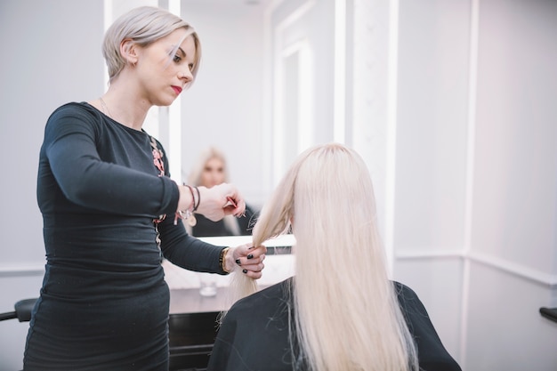 Foto gratuita peluquería profesional que peina el cabello del cliente