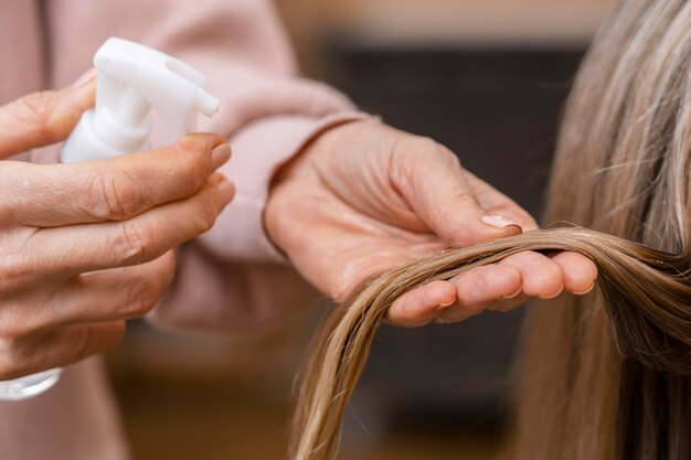 Peluquería sosteniendo un mechón de cabello y rociando con agua