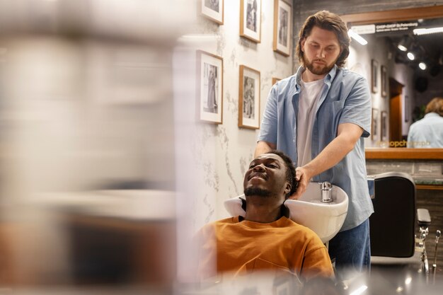 Peluquería de tiro medio lavando el cabello del hombre.