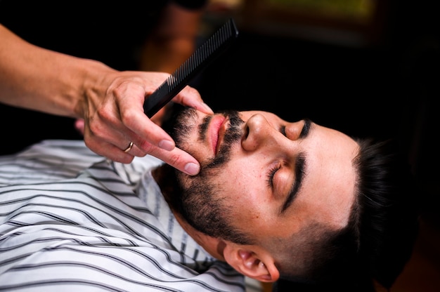 Peluquero de alto ángulo mirando la barba del cliente