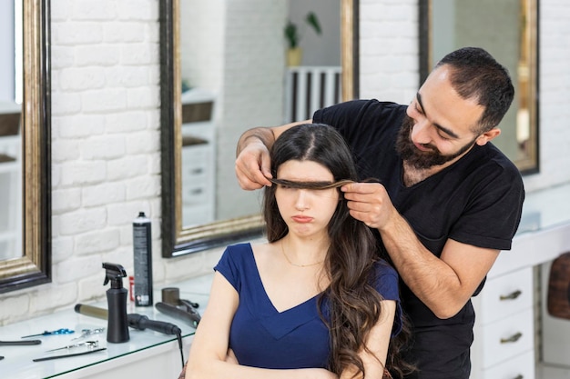 Peluquero divertido sosteniendo el cabello del cliente en su cara Foto de alta calidad