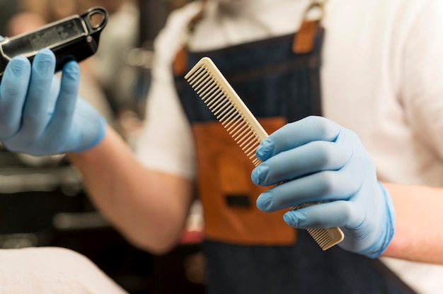 Peluquero con guantes de látex con recortador y peine