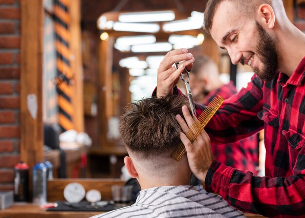 Peluquero guapo haciendo un corte de pelo hipster