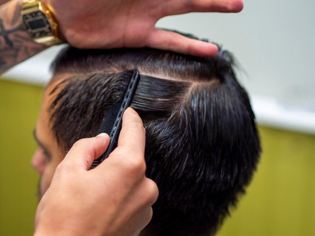 Peluquero haciendo un camino de pelo en el cabello de su cliente