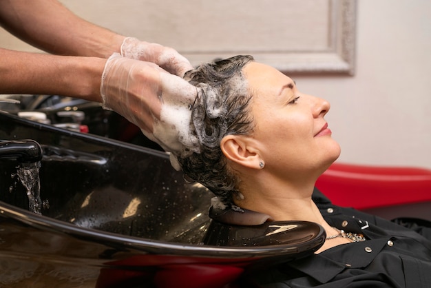 Peluquero lavando el cabello de una mujer