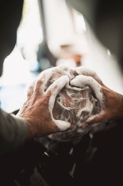 Peluquero masajeando champú en cabello con calvicie
