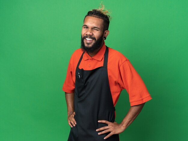 Peluquero masculino afroamericano joven alegre vistiendo uniforme