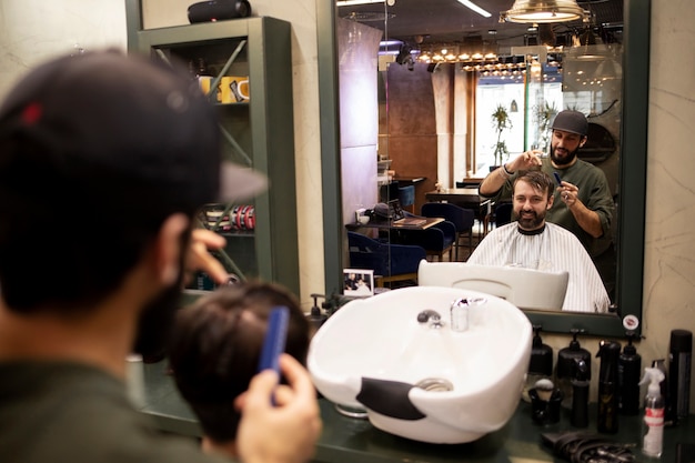 Peluquero masculino dando a su cliente un bonito corte de pelo