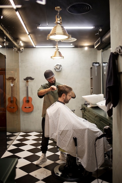 Peluquero masculino dando a su cliente un bonito corte de pelo