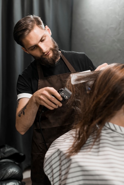 Peluquero masculino que corta el pelo del cliente