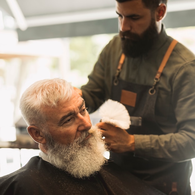 Peluquero profesional con brocha de afeitar y antiguo cliente masculino