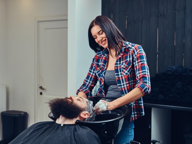 Peluquero profesional lavando el cabello de los clientes en una barbería.