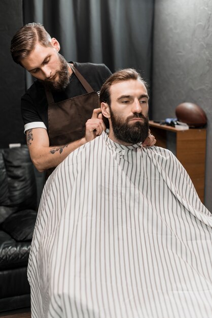 Peluquero profesional masculino que corta el pelo del cliente