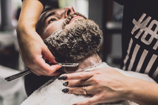 Peluquero que afeita al hombre en la tienda